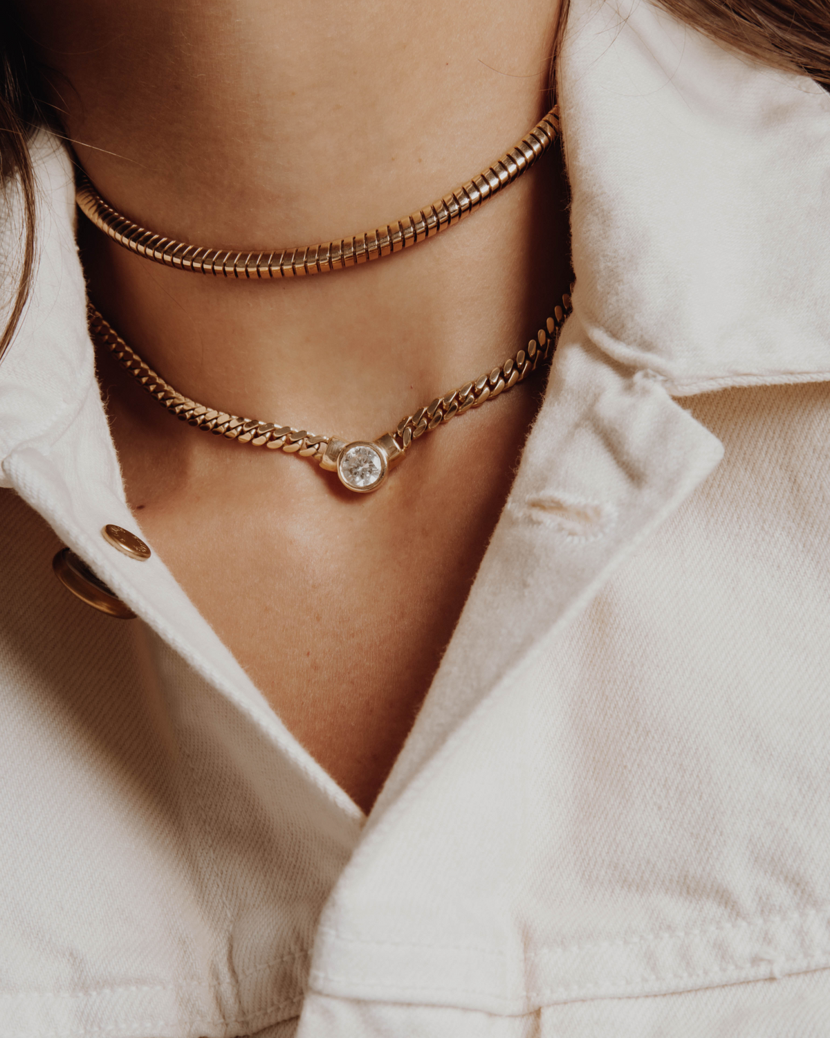 Close-up of a person wearing gold necklaces with a neutral background