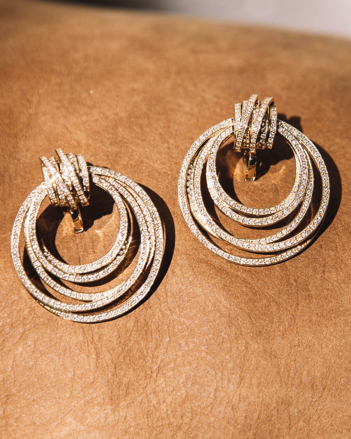 Pair of gold hoop earrings with diamond accents on a brown surface
