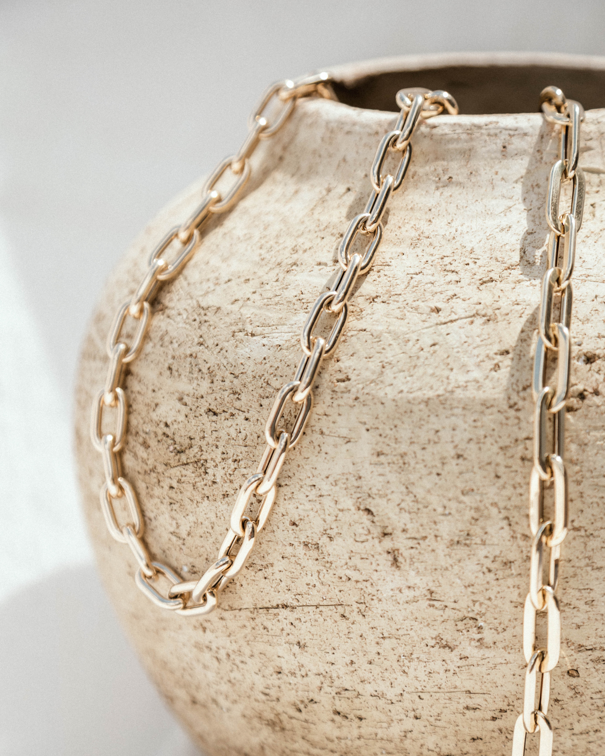 Gold chain necklace on a textured beige surface