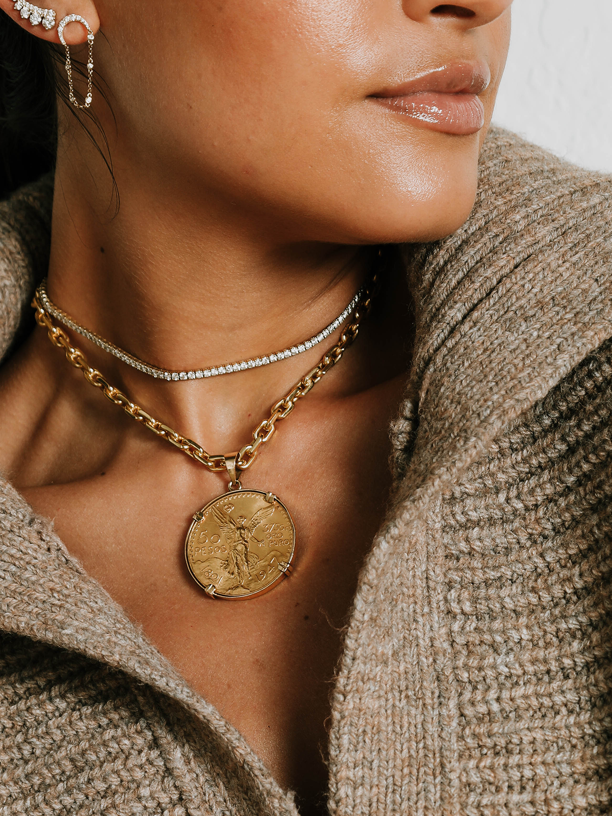 Close-up of a person wearing gold necklaces with a coin pendant.